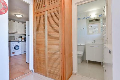 uma casa de banho com uma porta de madeira que leva a um WC e lavatório em Apartment Rio by vamdays em Moraira