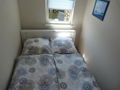 ein Bett mit zwei Kissen und einem Fenster in der Unterkunft Bungalow Mandy in Zinnowitz