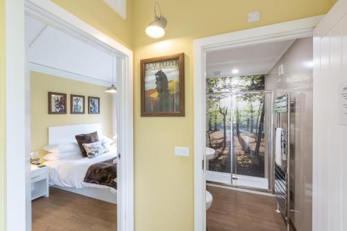 a bedroom with a bed and a bathroom with a window at Squirrel Lodge 43 with Hot Tub in Newton Stewart