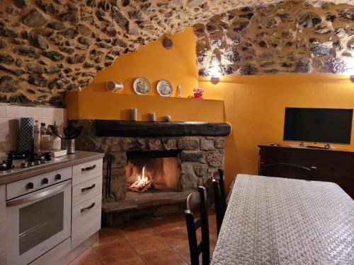 a kitchen with a fireplace with a table and a television at La Casa sull' Altopiano Mountain Lake Iseo hospitality in Bossico