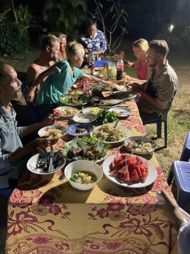 een groep mensen die rond een tafel zitten met borden eten bij Mada Lanta Mai Keaw in Koh Lanta