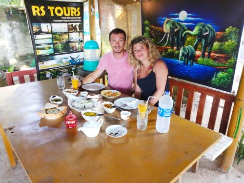 a man and woman sitting at a table with food at Rosa Shashi Cabanas in Galle