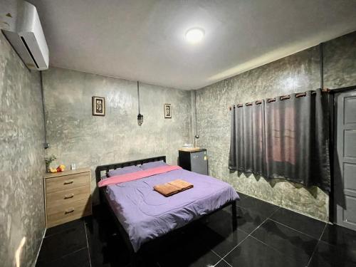 una camera da letto con un letto con lenzuola viola e una finestra di ดีต่อใจ รีสอร์ท เชียงม่วน Deetorjai Resort a Chiang Muan