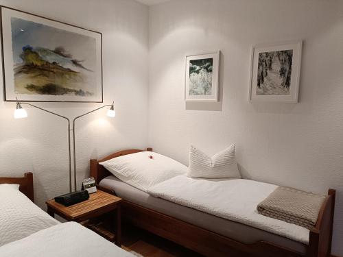Cette petite chambre comprend deux lits et une lampe. dans l'établissement Apartment HAUS MERLIN am Böckelsberg, à Weimar