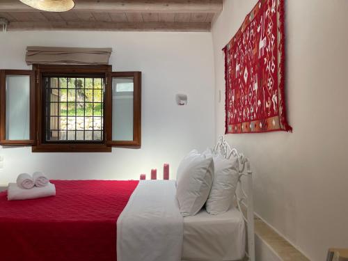 a bedroom with a bed with a red blanket and a window at Chelidonofolia in Skhinokápsala