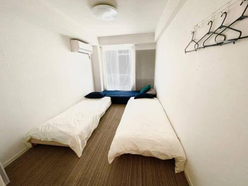 Cette chambre comprend 2 lits et une fenêtre. dans l'établissement SIMPLY WHiTE GUEST ROOM302, à Osaka