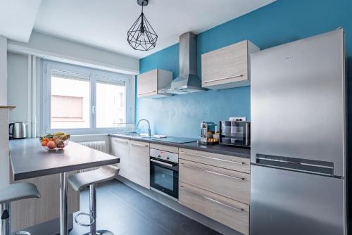 uma cozinha com paredes azuis e electrodomésticos em aço inoxidável em Le Lys - Calme à 5 min tram, proche centre Stras em Estrasburgo