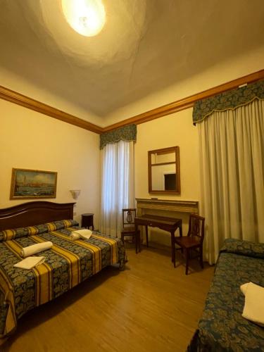 a hotel room with two beds and a desk at Hotel Alla Fava in Venice