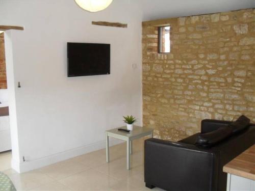 a living room with a couch and a tv on a wall at Mole Hole in Towcester