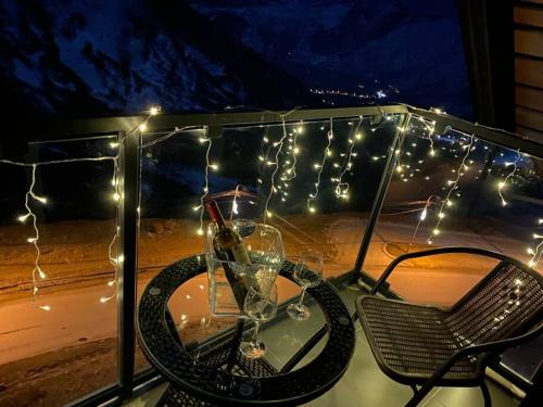 a table with a wine glass and lights on a balcony at Duplex in four seasons new gudauri near gondola in Gudauri