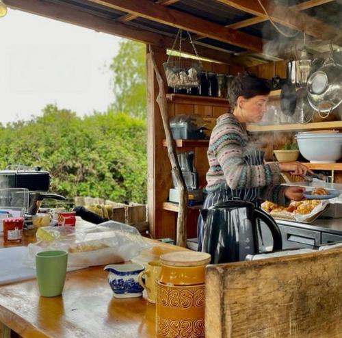a woman is preparing food in a kitchen at Delightful Shepherd hut in Graffham