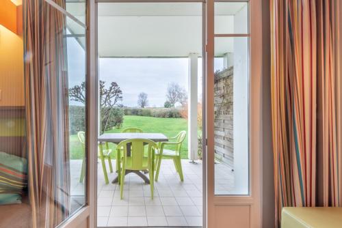 une porte en verre menant à une terrasse avec une table et des chaises. dans l'établissement Ar Mor 603, à Courseulles-sur-Mer
