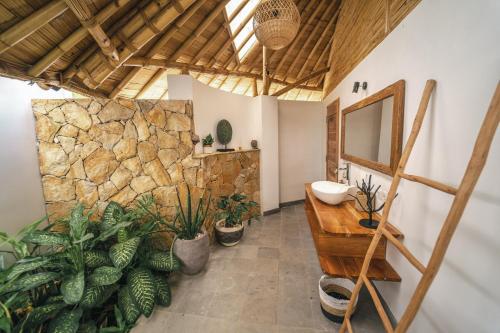 a bathroom with a sink and a stone wall at Kayuma Villas Lombok in Selong Belanak