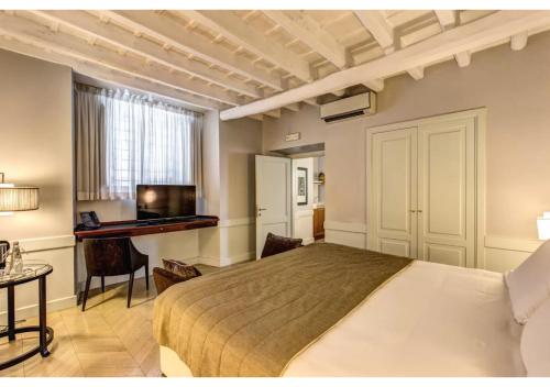 a bedroom with a bed and a desk and a television at Suites Giulia in Rome