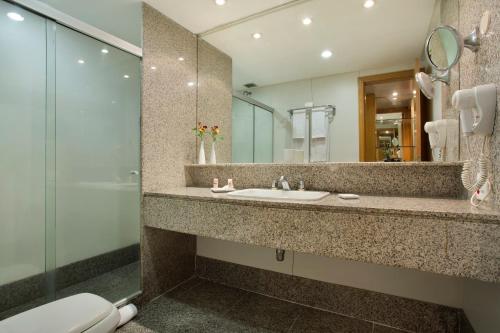 a bathroom with a sink and a mirror and a toilet at Royal Rio Palace Hotel in Rio de Janeiro