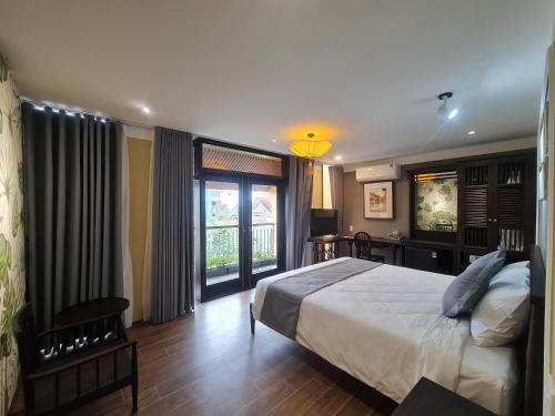a bedroom with a bed and a desk and windows at Hoianan Boutique Hotel in Hoi An
