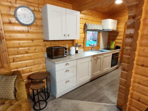 a kitchen with white cabinets and a clock on the wall at Parkwood Lodge in Louth