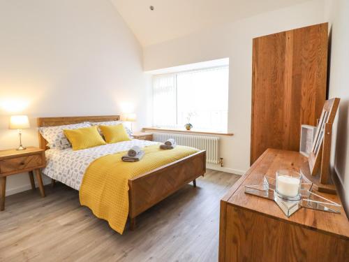 a bedroom with a bed with a yellow blanket on it at 3 Mountain View in Llangefni