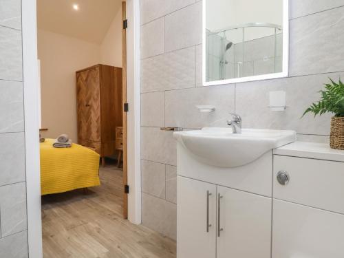 uma casa de banho branca com um lavatório e um espelho em 3 Mountain View em Llangefni