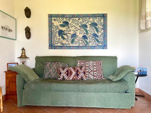 a green couch with pillows in a living room at CAPO CODA CAVALLO VILLA SALINEDDA GIARDINO VISTA MARE in Capo Coda Cavallo