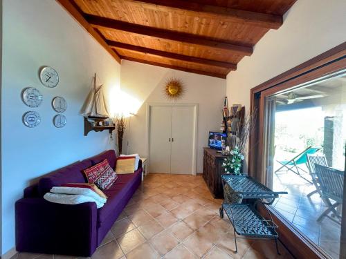 a living room with a purple couch and a window at CAPO CODA CAVALLO VILLA SALINEDDA GIARDINO VISTA MARE in Capo Coda Cavallo