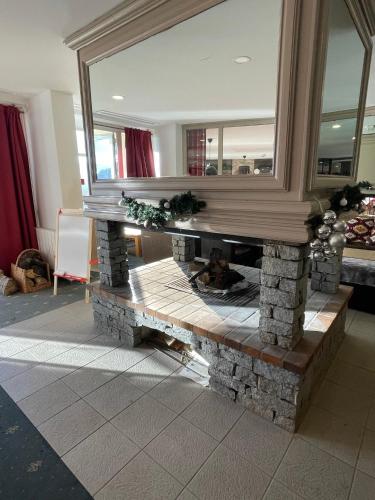 a stone fireplace in a living room with a mirror at Appart 4/5 pers résidence 4* des Bergers pieds des pistes in L'Alpe-d'Huez