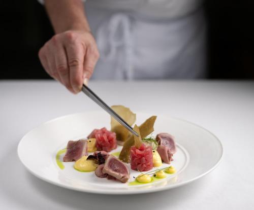 a person cutting a plate of food with a knife and fork at Baglioni Resort Maldives - Luxury All Inclusive in Dhaalu Atoll