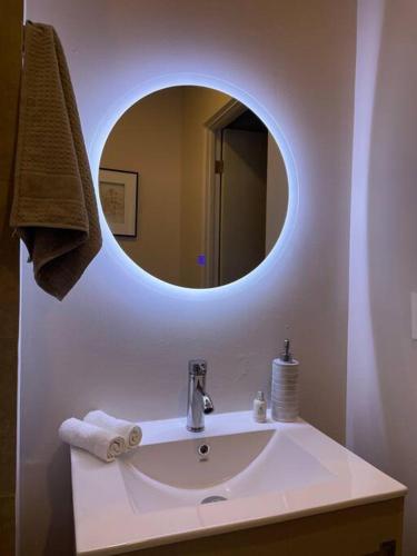 a bathroom with a sink with a round mirror at Exclusivo departamento a un lado de la Arena Mty, Fundidora y Cintermex in Monterrey