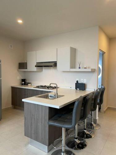 a kitchen with a sink and a counter with chairs at Exclusivo departamento a un lado de la Arena Mty, Fundidora y Cintermex in Monterrey
