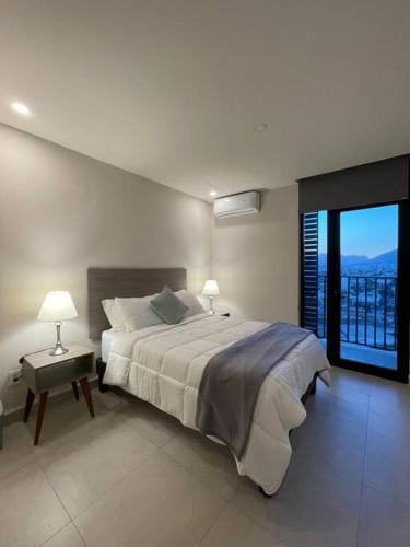 a bedroom with a large bed and a large window at Exclusivo departamento a un lado de la Arena Mty, Fundidora y Cintermex in Monterrey