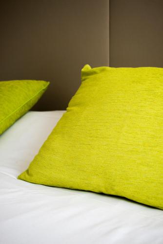 a bed with two lime green pillows on it at Campanile Hotel Nice Centre Acropolis in Nice