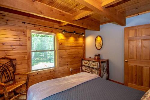 a bedroom with wooden walls and a bed and a window at The Hive at Blue Spruce Lodge White Mnts View in Brownfield