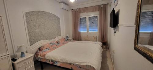 ein kleines Schlafzimmer mit einem Bett und einem Spiegel in der Unterkunft Maison climatisée avec solarium, wifi et piscine in Orihuela