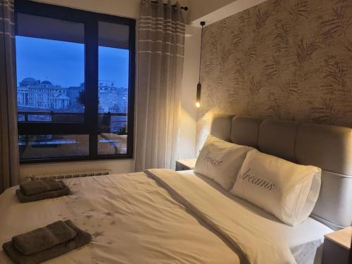 a large white bed with two pillows and a window at BS Apartment in Skopje