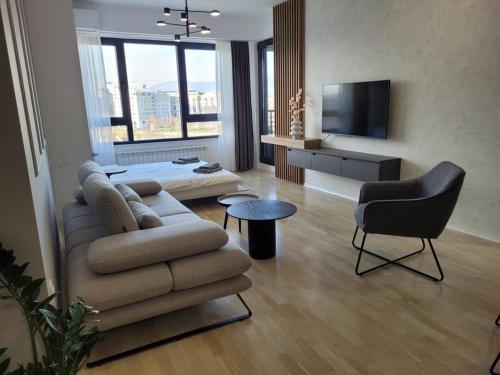 a living room with a couch and a bed and a television at BS Apartment in Skopje