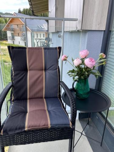 a chair with a vase of flowers on a balcony at KLINOVEC APARTMENTS LUXURY in Loučná pod Klínovcem