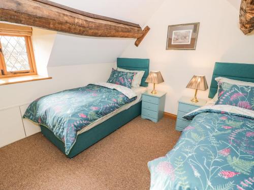 a bedroom with two beds and two lamps at Keepers Cottage in Ludlow