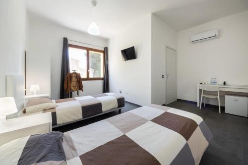 Habitación de hotel con 2 camas y escritorio en B&B Il Sogno di Mario, en Carbonia