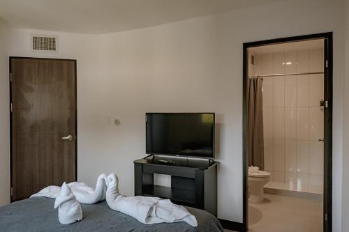 a bedroom with a bed with white sheets and a tv at Departamento de lujo en la playa in Jacó