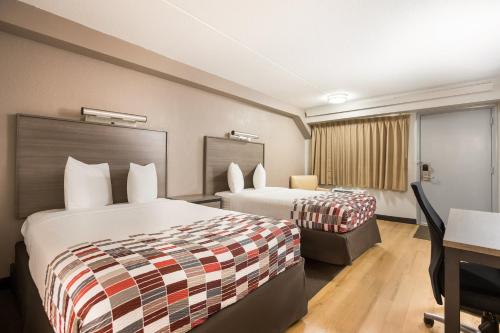 a hotel room with two beds and a desk at Red Roof Inn Princeton - Ewing in Lawrenceville