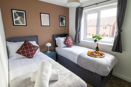 a bedroom with two beds and a window with a bowl of fruit at The Cosy House with Free Parking, Garden and Smart TV with Netflix by Yoko Property - Perfect for Contractors, Groups & Relocation in Leamington Spa