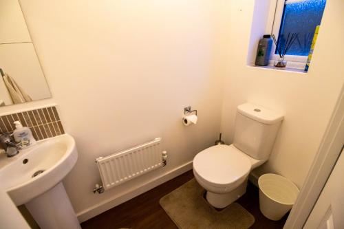a bathroom with a white toilet and a sink at The Cosy House with Free Parking, Garden and Smart TV with Netflix by Yoko Property - Perfect for Contractors, Groups & Relocation in Leamington Spa