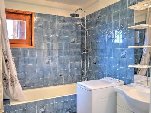 une salle de bain carrelée bleue avec douche et toilettes dans l'établissement Appartement rénové, skis aux pieds, proche centre avec parking et balcon - FR-1-524-30, à Morzine