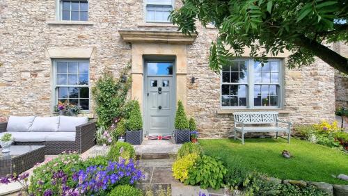 uma casa com uma porta branca e um banco no quintal em Rock View, Wensleydale em Leyburn