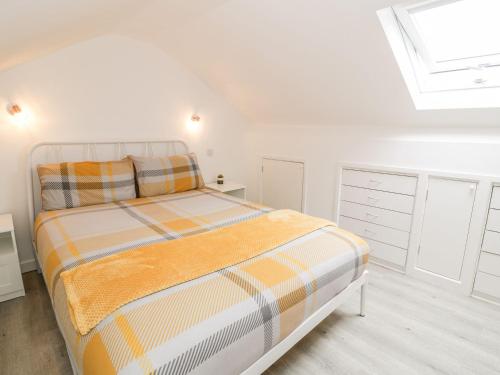 a white bedroom with a bed and a skylight at Cartref Clyd 55 in Porthmadog