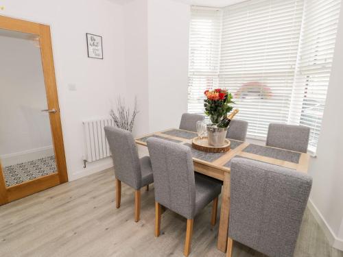 a dining room table and chairs with a vase of flowers at Cartref Clyd 55 in Porthmadog