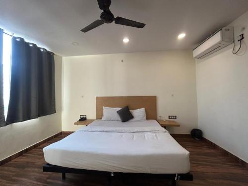 - une chambre avec un grand lit blanc et un ventilateur de plafond dans l'établissement The Chaitanya United Stay, à New Delhi