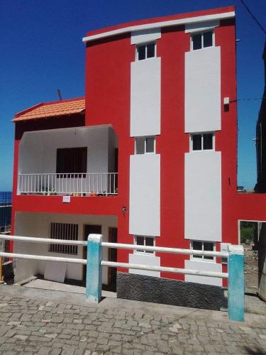 a red and white building with a fence in front of it at Pousada Cantinho de Preta in Seladinha
