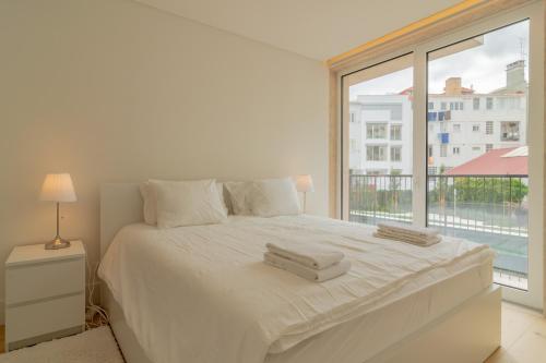 a bedroom with a white bed with a large window at Bright 1 BDR Apartment W/ Pool View by LovelyStay in Lisbon