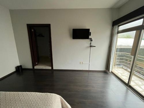a room with a bed and a television on a wall at Habitación Ojo de Agua in Orizaba